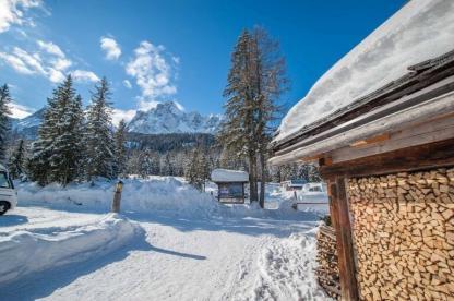 Caravan Park Sexten Camping Stellplätze im Schnee mit Bergen und blauem Himmel
