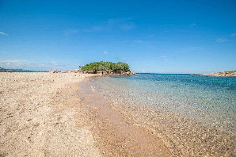 Strand mit glasklarem Wasser und Insel auf Sardinien