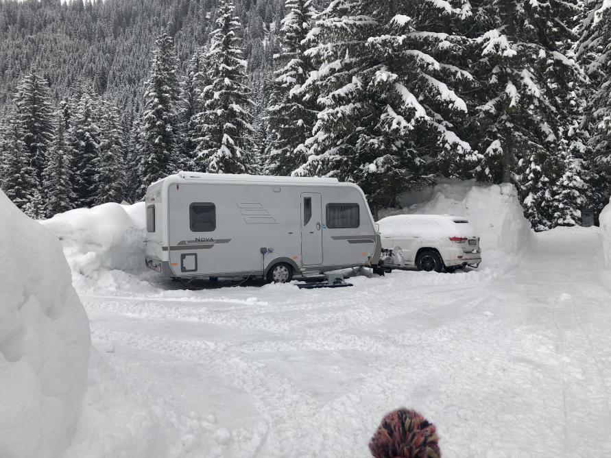 wohnwagen mit auto im schnee auf dem campingplatz